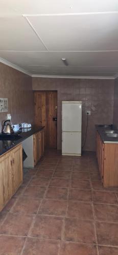 a kitchen with a white refrigerator and wooden cabinets at Safari Park Guest Farm in Colesberg
