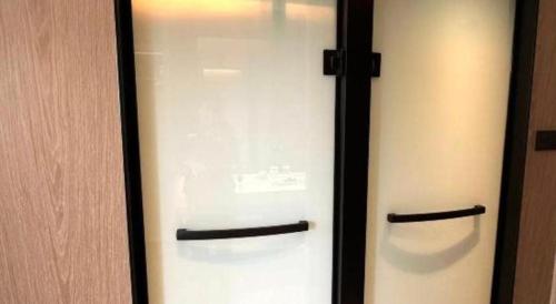 a glass door with two refrigerators in a room at Tianrun International Hotel in Dunhuang