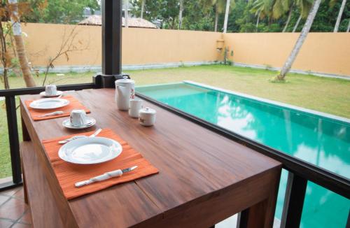 a table with plates of food on it next to a swimming pool at Breeze Villa Unawatuna in Galle