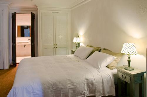 a bedroom with a white bed and a table with a lamp at Broken Hill Outback Church Stay in Broken Hill