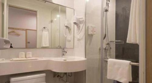 a white bathroom with a sink and a shower at Cozy Hotel Xiamen in Xiamen
