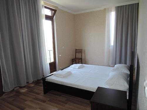 a bedroom with a bed with white sheets and a window at Shaloshvili's Cellar Hotel in Shilda