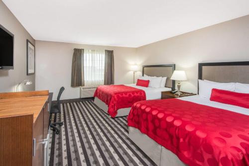 a hotel room with two beds and a flat screen tv at Ramada by Wyndham Springfield North in Springfield