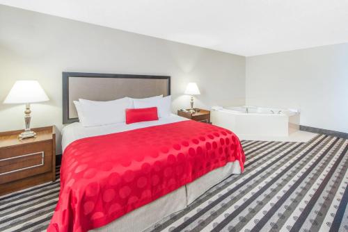 a hotel room with a large bed with a red bedspread at Ramada by Wyndham Springfield North in Springfield