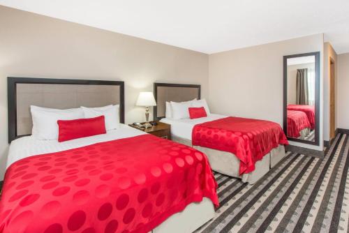 a hotel room with two beds with red covers at Ramada by Wyndham Springfield North in Springfield
