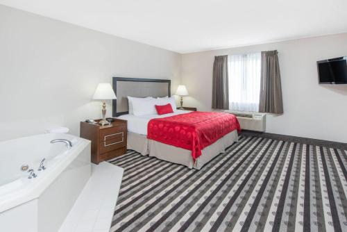 a hotel room with a bed and a bath tub at Ramada by Wyndham Springfield North in Springfield