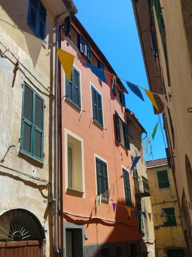 a building with flags hanging from it in a street at Il Cuore del Borgo - Holiday Home in Borgomaro