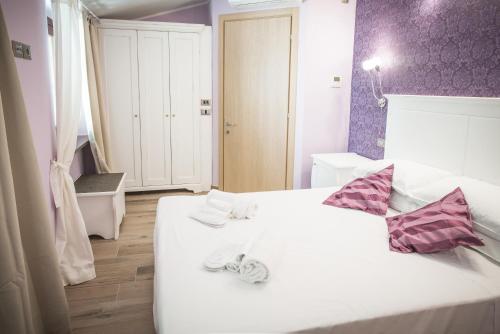 a bedroom with a white bed with purple walls at La Dimora di Francesco in Assisi