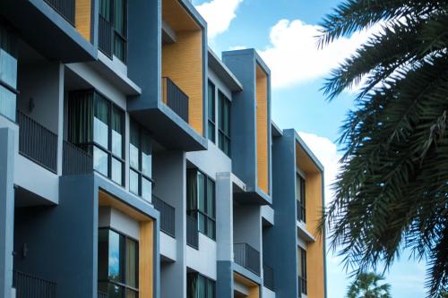 an apartment building with balconies and a palm tree at The Zense Boutique Hotel in Phitsanulok