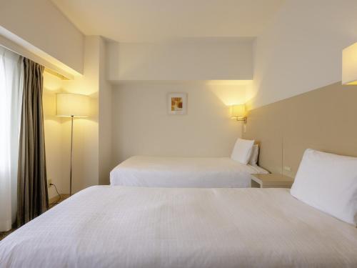 a hotel room with two beds and a window at KOKO HOTEL Tokyo Nishikasai in Tokyo