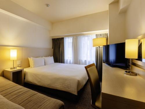 a hotel room with two beds and a flat screen tv at KOKO HOTEL Tokyo Nishikasai in Tokyo