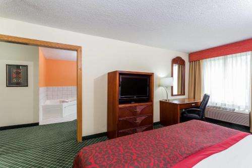 a hotel room with a bed and a flat screen tv at Days Inn & Suites by Wyndham Bloomington/Normal IL in Bloomington