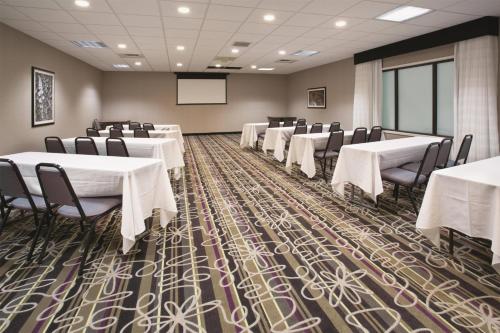 a conference room with tables and chairs and a screen at La Quinta by Wyndham Denver Englewood Tech Ctr in Greenwood Village