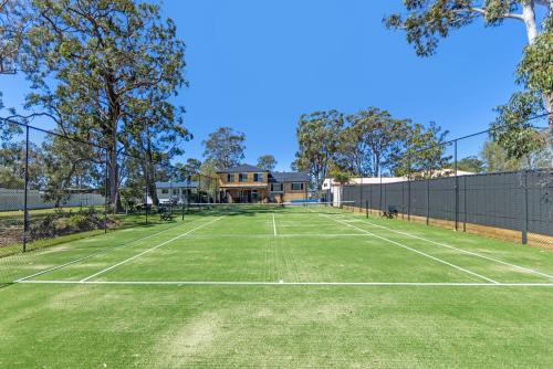 a tennis court with a house in the background at Anglesey - Pet Friendly with Pool - 4 Mins Walk to Beach in Callala Bay