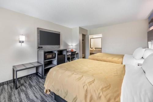a hotel room with two beds and a flat screen tv at Quality Inn Glasgow in Glasgow