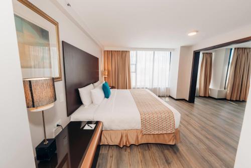 a hotel room with a bed and a lamp at La Quinta by Wyndham Quito in Quito