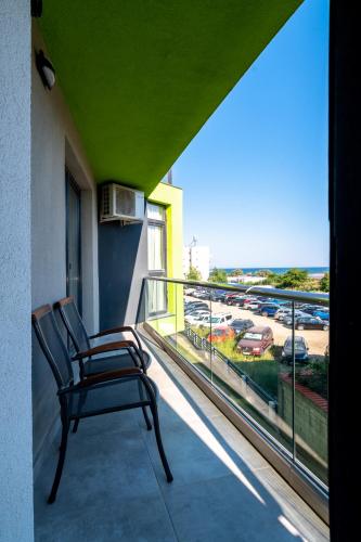 a chair on a balcony with a view of a parking lot at Apartamente Miramare by Alz in Mamaia Sat/Năvodari