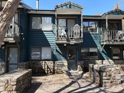 a blue house with a stone wall at Three Bears 2 - Thredbo in Thredbo