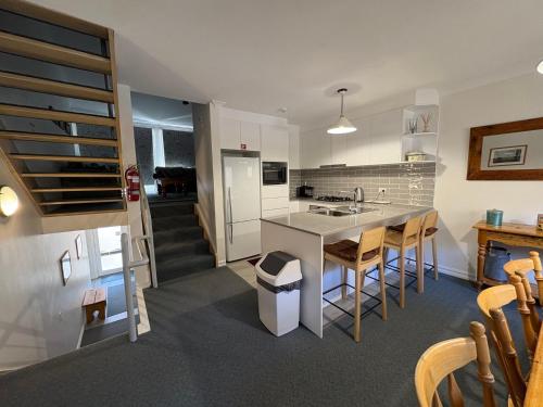 a kitchen with a sink and a counter with chairs at Three Bears 2 - Thredbo in Thredbo