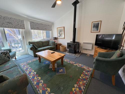 a living room with a coffee table and a television at Three Bears 2 - Thredbo in Thredbo