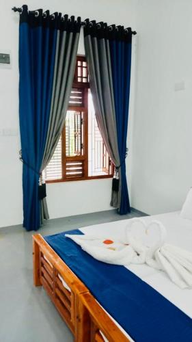 a bedroom with a bed with blue curtains and a window at Coastal Heaven in Pottuvil