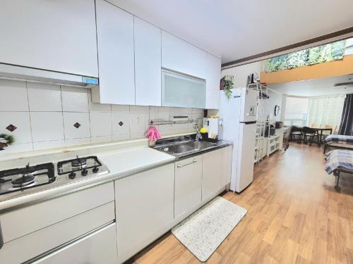 a white kitchen with a sink and a stove at Like U Residence in Goyang