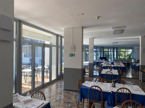 a dining room with tables and chairs with blue tables at Hotel Helvetia in Grado