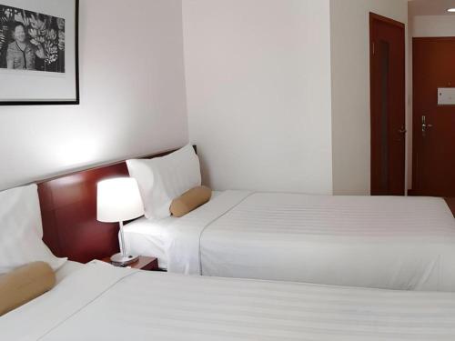 two beds in a hotel room with white sheets at PARK HOTEL Cawang Jakarta in Jakarta