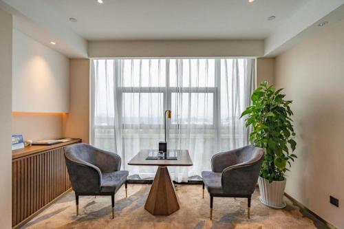 a room with two chairs and a table in front of a window at Grand Metropark Hotel Chongqing in Chongqing