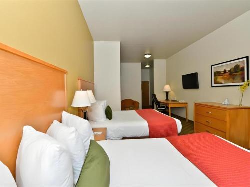 a hotel room with two beds and a desk at Best Western Plus Guymon Hotel and Suites in Guymon