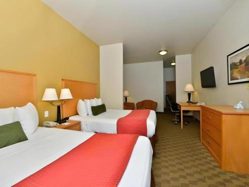 a hotel room with two beds and a desk at Best Western Plus Guymon Hotel and Suites in Guymon