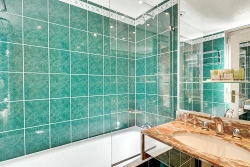 y baño con ducha de azulejos verdes y lavabo. en Villa Luxembourg, en París