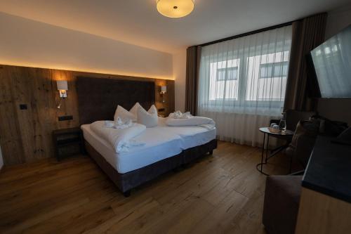a hotel room with a bed with white pillows at Alpenhotel Regina in Nauders