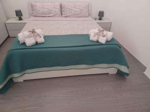 a bedroom with a bed with a green comforter and towels at Casa Francy in Alghero
