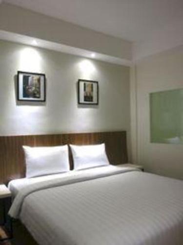a bed in a room with two pictures on the wall at Hart Hotel Arjuna in Gili Trawangan