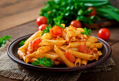 a plate of pasta with tomatoes on a table at Block K in New Delhi