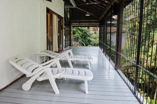 a row of white lounge chairs on a porch at LilyJoe Treehouse Serendah in Serendah