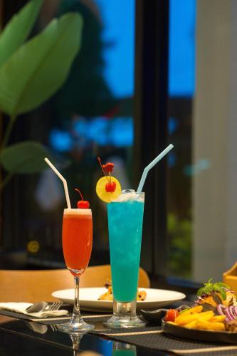 two cocktails on a table with plates of food at The Zense Boutique Hotel in Phitsanulok