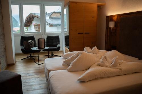 a bed with white sheets and pillows in a room at Alpenhotel Regina in Nauders