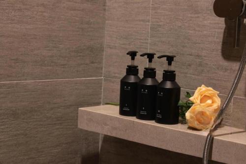 a group of four black bottles on a shelf in a bathroom at Atour Hotel Weihai Shidao in Dongshan