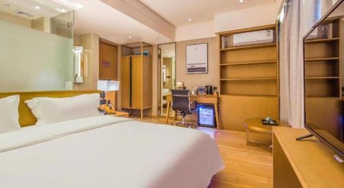 a bedroom with a bed and a desk with a computer at V8 Ziyuangang Hotel in Guangzhou