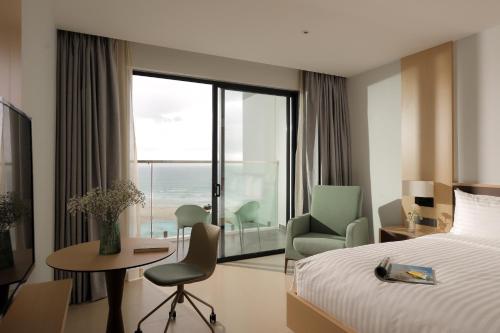 a hotel room with a bed and a desk and a chair at THE SEA at THE ARINA CAM RANH in Thôn Hò Ða