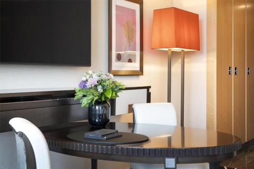 a dining room table with a vase of flowers on it at Waldorf Astoria Berlin in Berlin