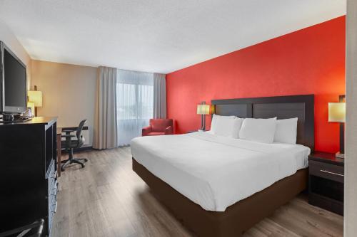 a hotel room with a large bed and a red wall at Quality Inn & Suites 5585 Ambler Drive Mississauga Ontario in Mississauga