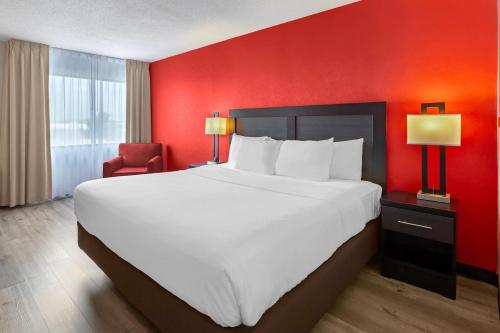a large bed in a hotel room with a red wall at Quality Inn & Suites 5585 Ambler Drive Mississauga Ontario in Mississauga