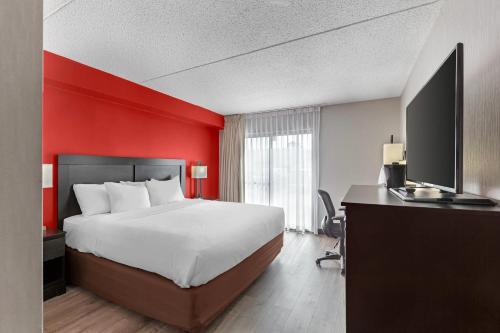 a hotel room with a bed and a red wall at Quality Inn & Suites 5585 Ambler Drive Mississauga Ontario in Mississauga