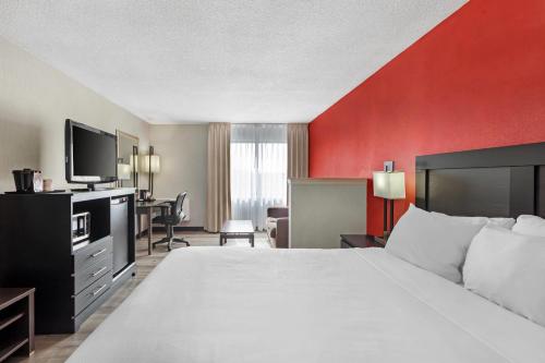 a hotel room with a large bed and a red wall at Quality Inn & Suites 5585 Ambler Drive Mississauga Ontario in Mississauga