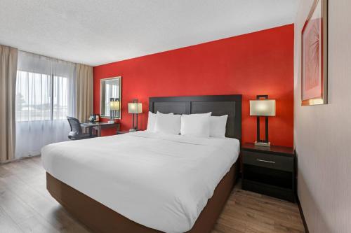 a large bed in a hotel room with a red wall at Quality Inn & Suites 5585 Ambler Drive Mississauga Ontario in Mississauga