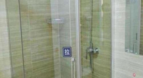 La salle de bains est pourvue d'une douche et d'un panneau sur la porte. dans l'établissement 7 Days Inn Huanggang Luotian Hedong Street Dabieshan Food Plaza, à Luotian