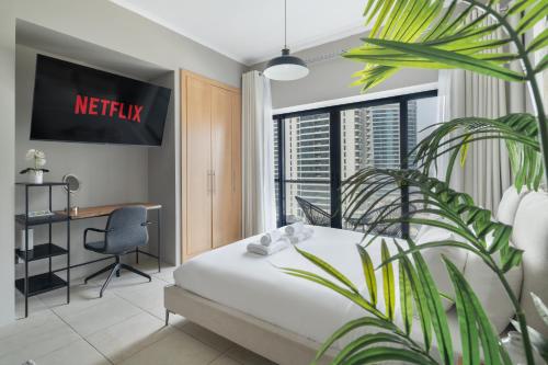 a hotel room with a bed and a desk and a plant at Chic JLT Studio, Lake View, Pool, Metro Access in Dubai